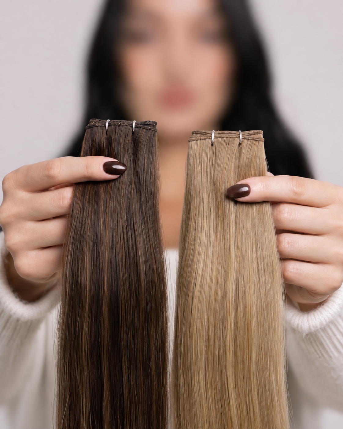 Stylist holding a brunette and a blonde weft side by side to compare construction